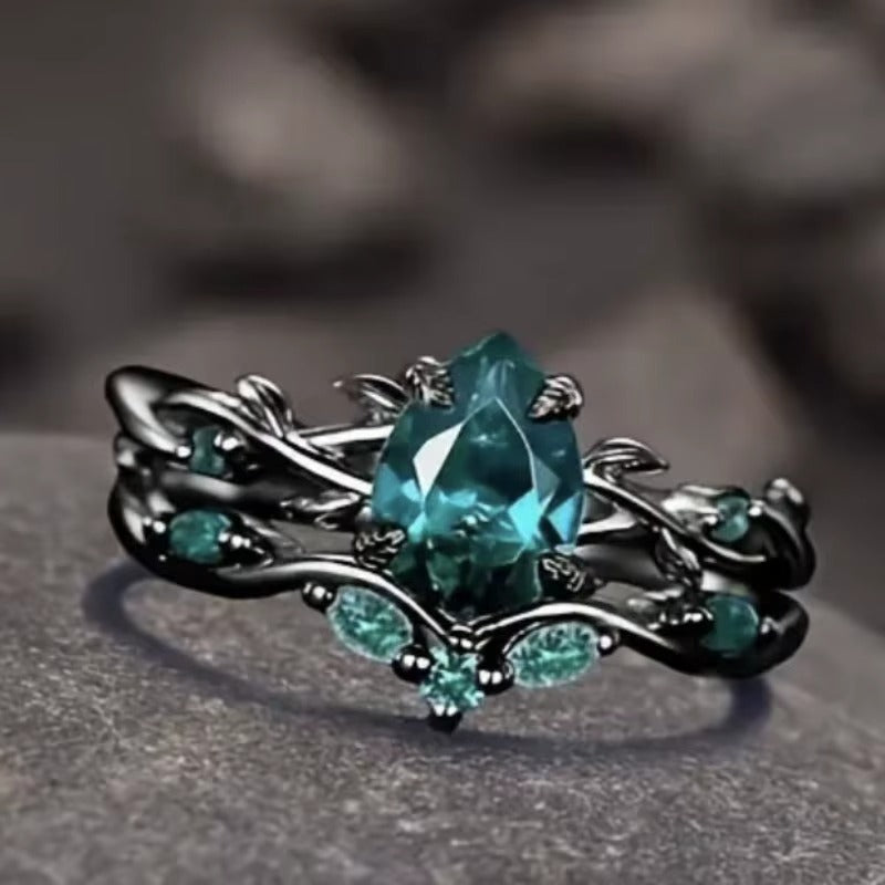Anello di Lusso con Pietra Centrale e Dettagli Floreali – Montatura Nera Elegante