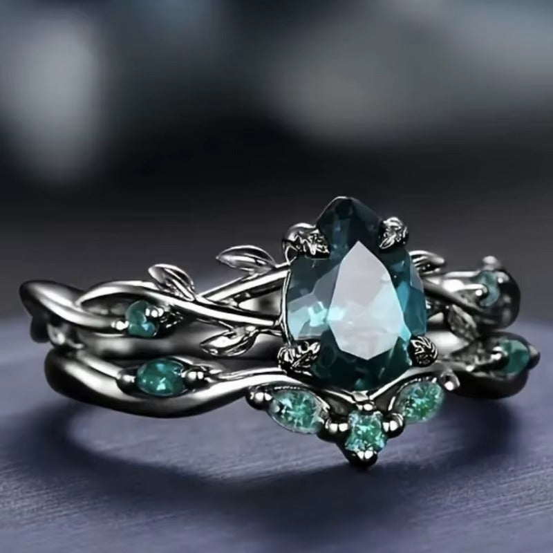 Anello di Lusso con Pietra Centrale e Dettagli Floreali – Montatura Nera Elegante